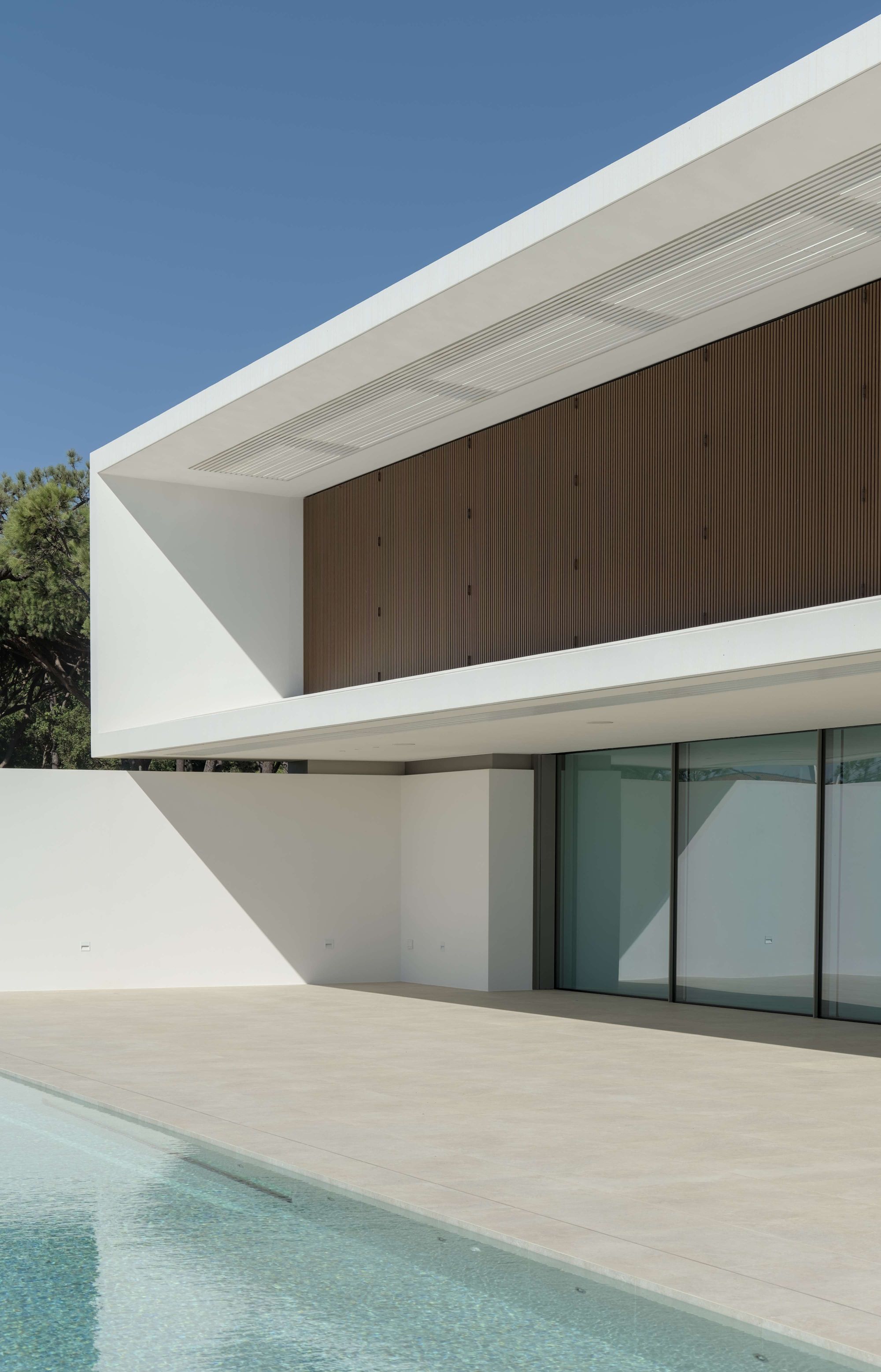 Pormenor da fachada de uma casa contemporânea onde se destaca um gradeamento metálico com textura de madeira