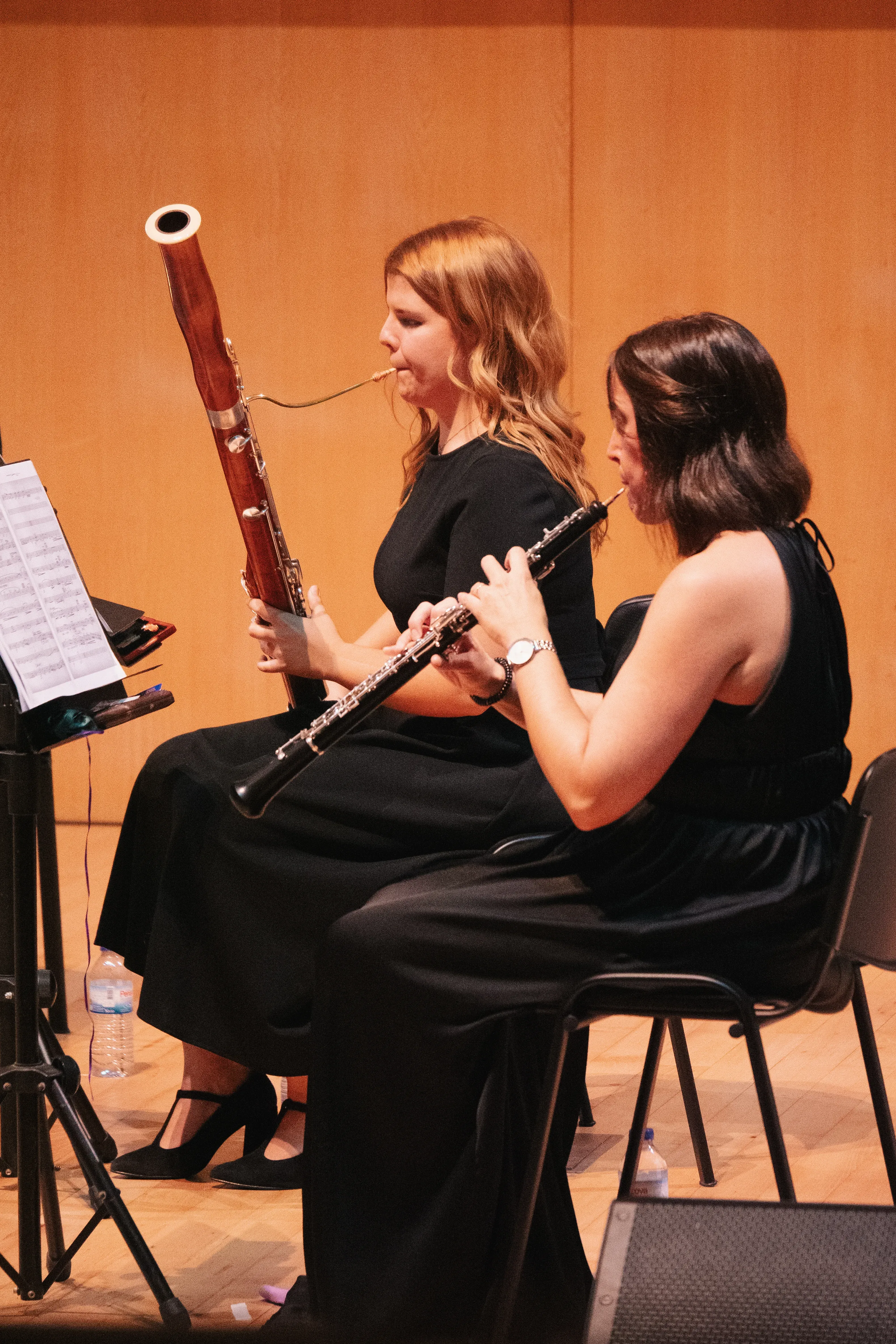 Duas performers tocam instrumentos de sopro num palco.